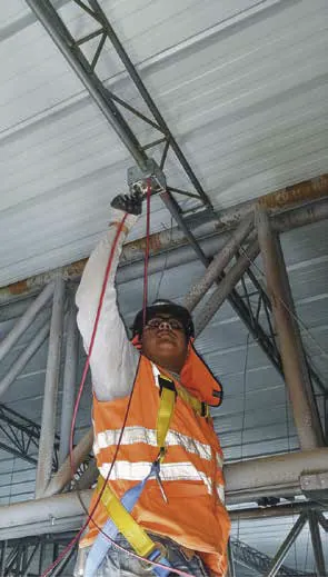 Técnico con arnés trabajando en altura sobre la estructura de una nave.