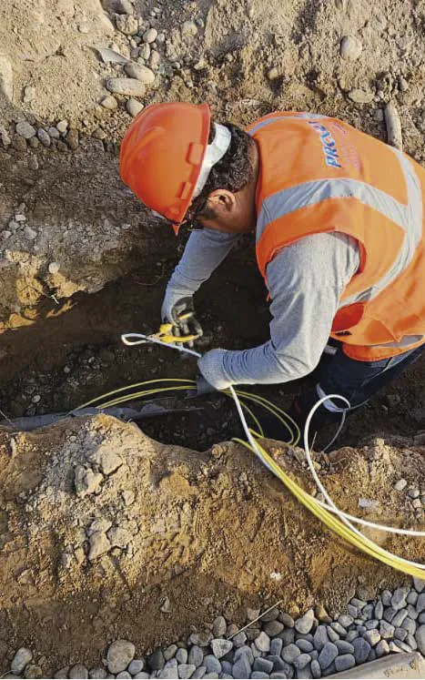 Técnico instalando cableado en una zanja de obra.